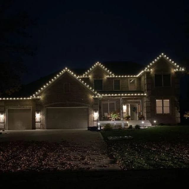 Warm white roofline lighting on a brick two-storey home in the Omaha metro