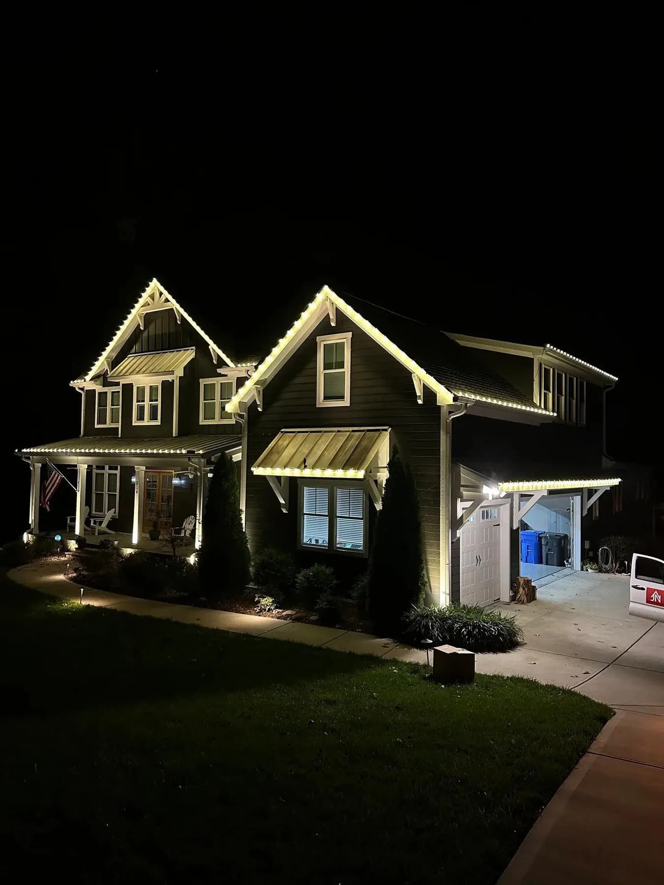 Warm white roofline lighting on the gables and awnings of a craftsman home near Omaha at night