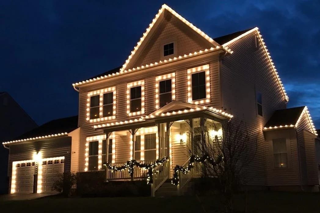 Warm white lighting outlining the windows, porch and garage of a white two-storey house